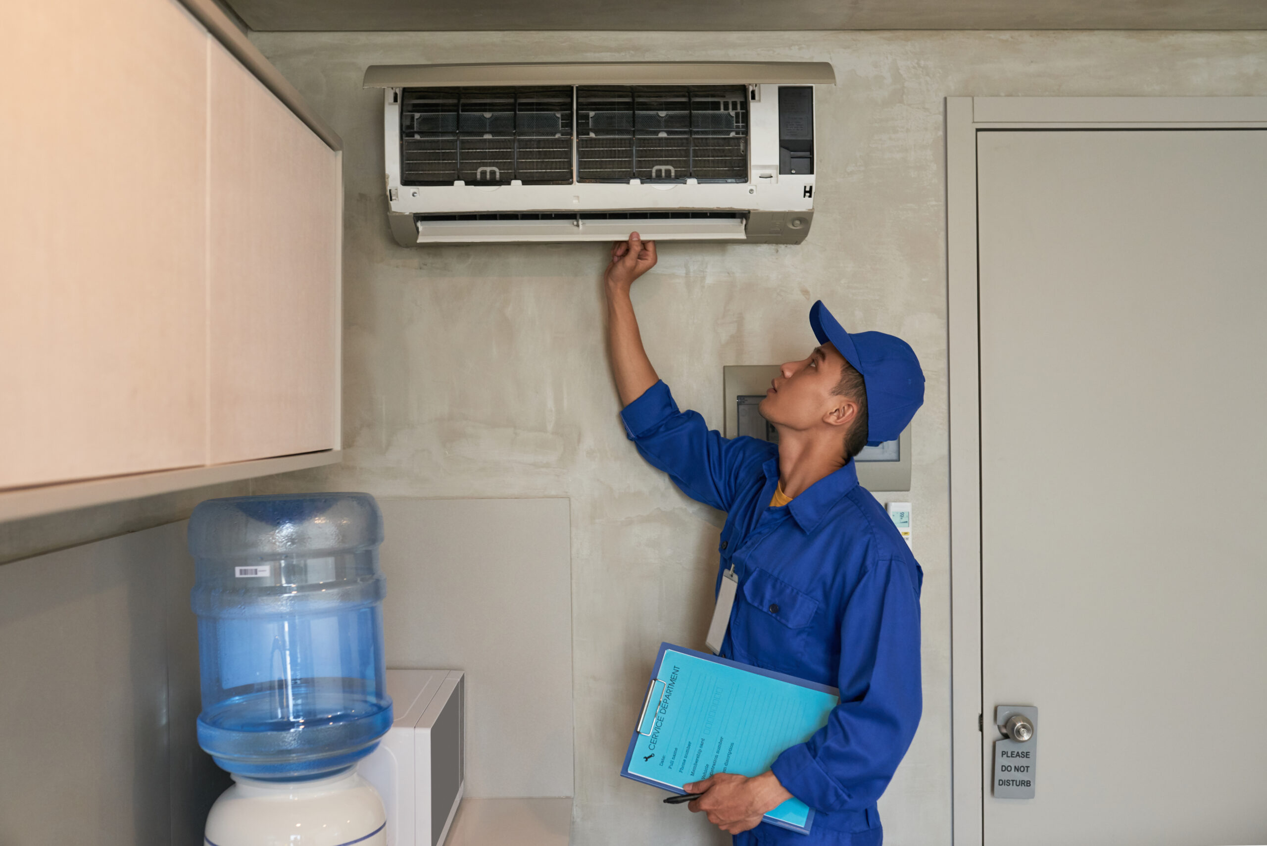 Young Asian technician checking conditioner in kitchen